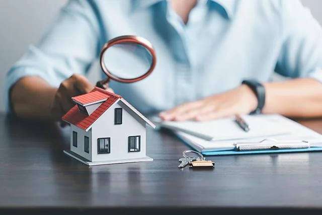Magnifying glass over a model house and keys